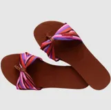 Sandalias Havaianas modelo You St Tropez con base de goma marrón y tira superior de tela con diseño de lazo a rayas multicolor.