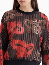 Buzo de punto calado con estampado full print en tonos rojos, marrones y negros. Presenta mangas amplias y terminaciones en cuello, puños y cintura en tela negra que genera contraste.
