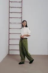 Pantalon de corte amplio y relajado en color verde, con pinzas delanteras, botones decorativos y cinturón de lona incluido.