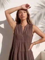 Vestido corto de lino natural color blanco, sin mangas, con cuello mao y escote en V con botones de nácar. Presenta diseño escalonado con volados fruncidos en la falda.