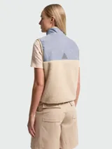 Chaleco de diseño híbrido con cuerpo de tejido de peluche en color beige y canesú superior de cambray en tono azul claro. Presenta cierre frontal completo, bolsillos laterales con cierre y logo de la marca bordado en el pecho.