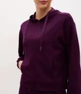 Campera deportiva de modal negro con capucha, cierre frontal por cremallera, cordones ajustables, bolsillos y mangas largas con puños elásticos.
