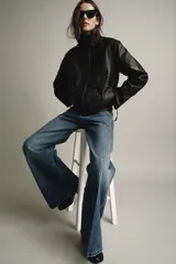 Chaqueta bomber de piel 100% color negro con efecto desgastado. Cuello alto, manga larga con cremalleras metálicas y bajo elástico. Bolsillos de plastrón con solapa y botón en el delantero. Cierre frontal con cremallera y botones a presión ocultos por solapa.