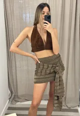 Minifalda color crudo con lurex dorado, diseño cruzado con nudo lateral y corte ajustado.