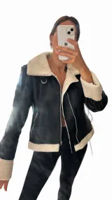 Campera gamulan de cuerina negra con forro de corderito color crema, cierre asimétrico con cremallera y hebilla en el cuello.