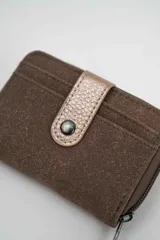 Billetera compacta de gamuza color beige con detalle de solapa central en cuero sintético marrón oscuro y cierre perimetral.