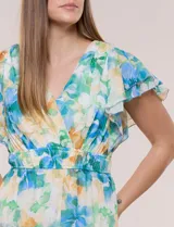 Vestido midi de gasa con estampado floral en tonos azules, verdes y amarillos, escote en V cruzado, mangas cortas con volados, cintura elastizada y bolsillos laterales.