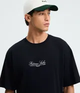Remera masculina negra de algodón, con corte boxy, mangas cortas y cuello redondo. Presenta un lettering bordado en blanco en la parte delantera con la frase "Palermo Sicilia".