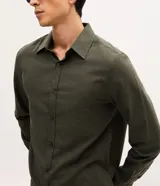 Camisa de manga larga con cuello inglés y cierre frontal de botones, confeccionada en tricolina de algodón color beige.