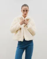 Campera corta de piel sintética en color crema, con cuello amplio tipo solapa y cierre frontal.