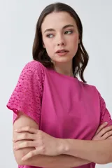 Remera fucsia de manga corta con detalle de broderie en las mangas.