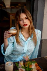 Camisa de broderie color celeste, con diseño de calados florales, mangas globo con puños y cuello camisero clásico.