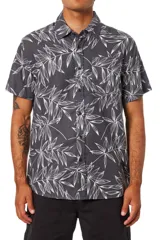 Camisa de manga corta Katin modelo Matcha, de color negro con estampado de hojas en tono blanco. Cuenta con cuello clásico, cierre frontal con botones y un bolsillo aplicado en el pecho.