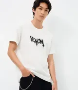 Remera de algodón color blanco, con cuello redondo y manga corta. Presenta una estampa frontal con el logo de Venom en estilo graffiti negro.