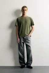 Jeans de denim de algodón en color azul con efecto desgastado, tiro medio y corte recto de ajuste holgado (loose fit). Cuenta con diseño clásico de cinco bolsillos y cierre frontal con cremallera y botón.