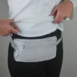Riñonera de viaje gris impermeable con cierre frontal y correa ajustable con hebilla plástica.
