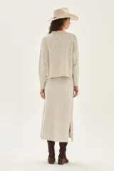Sweater de tejido bouclé color crudo con cuello alto y sutil brillo por hilos de lurex. Posee mangas largas y un calce relajado.