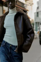 Chaqueta de cuello solapa y manga larga, con diseño de doble faz que combina tejido efecto ante y borreguillo. Cuenta con cierre frontal de botones y bolsillos delanteros.