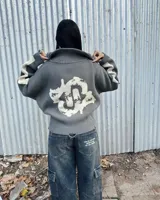Sweater gris de tejido de punto con cuello alto y cierre frontal parcial. Presenta diseño oversize con bandas blancas en las mangas y un gran gráfico blanco en la espalda.