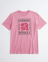 Remera de manga corta color fucsia con estampa frontal enmarcada con la frase Choose Wisely y diseño abstracto en el centro.