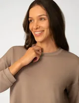 Buzo de punto color rosa, con cuello redondo y detalle de tejido crochet en el escote. Presenta mangas largas y un corte clásico con caída suave.