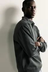 Sudadera polo de corte regular, confeccionada en tejido técnico interlock de algodón con elasticidad. Presenta cuello solapa, cierre frontal de cremallera y manga larga con puños acabados en rib.