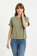 Remera blanca de algodón, de corte ajustado, con cuello redondo y mangas cortas terminadas con volados delicados.