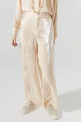 Pantalón de terciopelo color nude, de tiro alto, con cintura elástica en la espalda, cierre frontal, bolsillos laterales y piernas anchas.