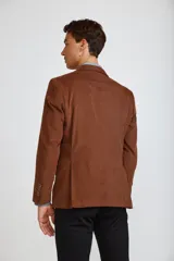 Blazer de pana color marrón oscuro, con cierre frontal de dos botones, solapas clásicas y bolsillos laterales con solapa. Presenta un diseño estructurado y elegante.