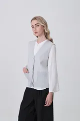 Chaleco de punto gris con escote en V, cierre frontal de botones y dos bolsillos delanteros con terminación acanalada.