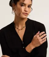 Camisa negra de viscosa sostenible, con escote en V, mangas largas abullonadas con puños elásticos y cierre frontal con botones. Presenta detalles de canalé en los hombros y la espalda.
