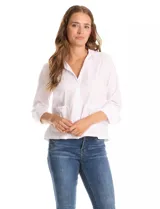 Camisa blanca de corte recto y estilo clásico, con cuello solapa, cierre frontal oculto y mangas largas con puños. Presenta dos bolsillos frontales decorados con apliques de tachas metálicas en el borde superior.