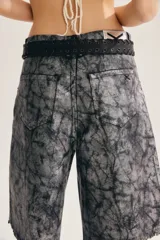Bermuda de denim color gris con efecto acid wash y acabado brillante, de calce amplio y oversized. Cuenta con diseño largo hasta la rodilla, roturas y ruedo deshilachado.