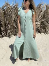 Vestido largo fucsia de lino, con corte recto, breteles anchos con volados y botones frontales. Presenta un tajo lateral.