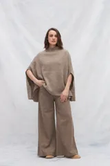 Poncho de tejido de punto industrial color marrón claro, con cuello alto y aberturas laterales para los brazos.