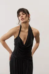 Top negro con diseño cruzado tipo halter, escote pronunciado y fruncido lateral.