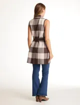 Chaleco tejido largo de la marca Absolutely Famous, con estampado a cuadros en tonos marrón, beige y blanco. Presenta cuello con solapa, abertura central, bolsillos aplicados en la parte delantera, pasadores en la cintura con lazo de ajuste y un tajo central en el ruedo trasero.