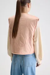 Chaleco reversible de calce relajado color rosado con escote en V y diseño acolchado. Cuenta con bolsillos laterales y cierre frontal de cremallera.