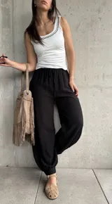 Pantalón negro tipo babucha con cintura elástica fruncida y cordón ajustable, corte holgado y puños elásticos en los tobillos.