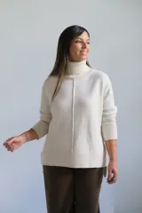 Sweater de punto color crudo con cuello alto, manga larga y detalle de costura vertical central. Presenta puños y ruedo acanalados.