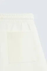 Bermuda de algodón color beige claro, corte relajado (relaxed fit), con cintura elástica ajustable mediante cordón y bolsillos laterales y trasero de plastrón.