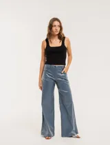 Pantalón de jean elastizado azul con terminación metalizada, corte wide leg, tiro medio, cierre delantero con botón, bolsillos laterales y traseros.