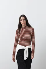 Polera de cuello alto y manga larga con diseño de rayas horizontales en color marrón y blanco. Confeccionada en tejido de algodón con elastano, presenta un calce ajustado al cuerpo.