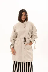 Trench de gabardina Tencel con silueta relajada, cierre frontal de botones, lazo ajustable y desmontable en la cintura, cuello alto, bolsillos laterales y lazos regulables en los puños.