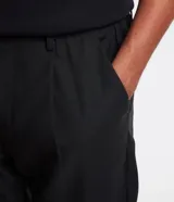 Pantalón de sastrería corte loose, color negro, con cintura con trabillas, cierre de botón y cremallera, y bolsillos laterales tipo cuchillo.