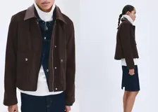 Chaqueta de algodón estilo tejano de corte recto, color marrón, con cuello camisero de efecto piel en contraste, manga larga y dos bolsillos de parche con solapa y botón en el frente. Cuenta con cierre oculto de cremallera y botones.