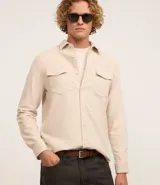 Camisa de manga larga confeccionada en terciopelo de algodón, con cuello clásico, cierre frontal de botones y dos bolsillos con solapa en el pecho.