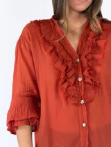 Blusa color óxido de manga larga con volados frontales y cierre con botones nacarados.