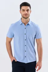 Camisa de piqué lisa color celeste, de manga corta, con cuello camisero y cierre frontal de botones oscuros.