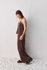 Pantalón wide leg de tiro medio y calce amplio, color marrón, con pinzas delanteras, cierre frontal y bolsillos laterales funcionales.